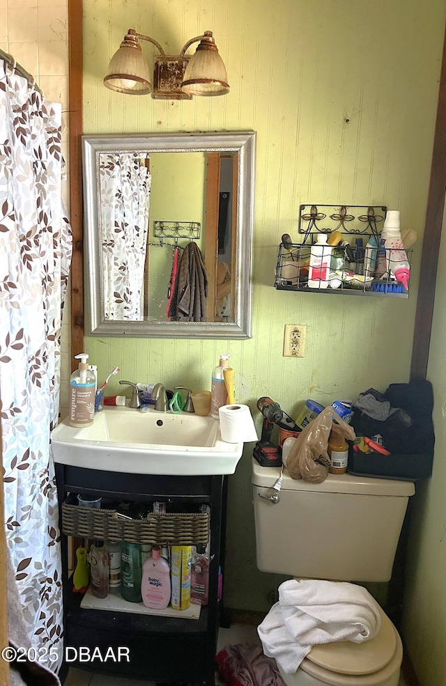 full bath featuring wooden walls, vanity, and toilet