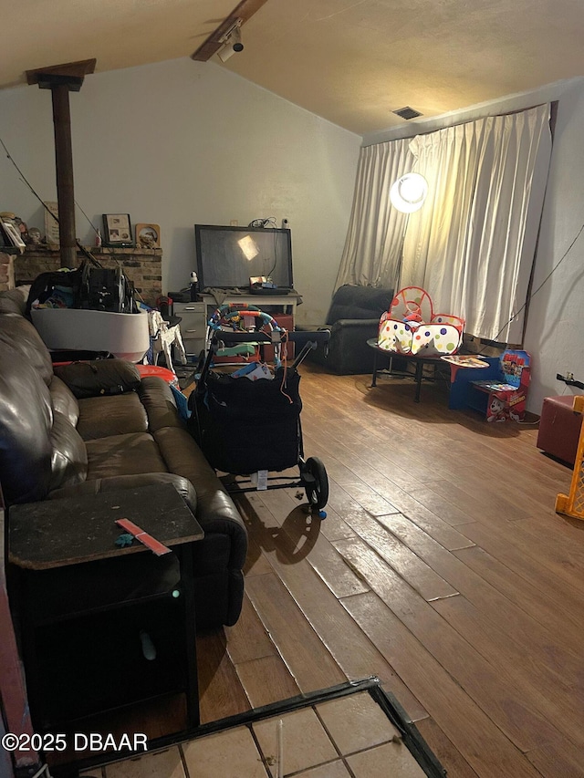living room with visible vents, hardwood / wood-style floors, and vaulted ceiling