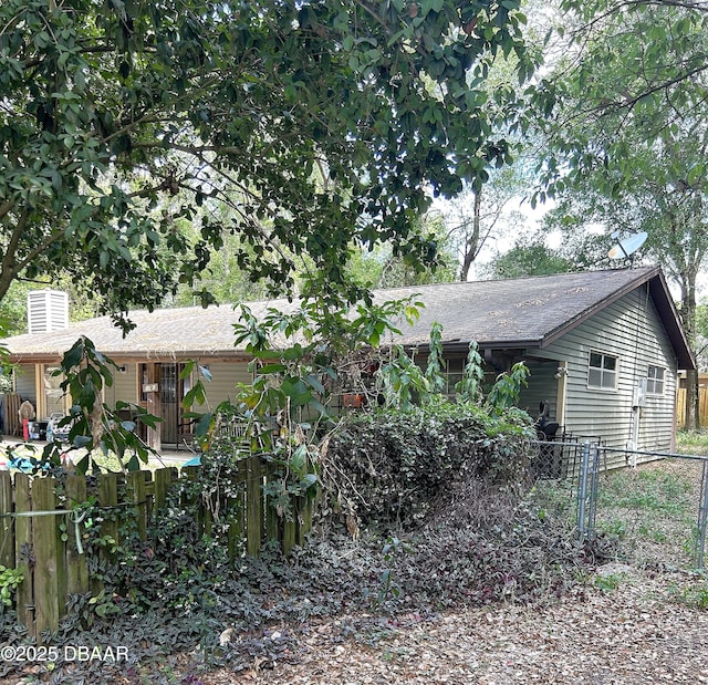 view of property exterior with fence, roof with shingles, and a chimney