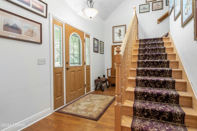 foyer entrance with hardwood / wood-style floors and vaulted ceiling