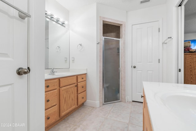 bathroom with vanity, a textured ceiling, an enclosed shower, and tile patterned flooring