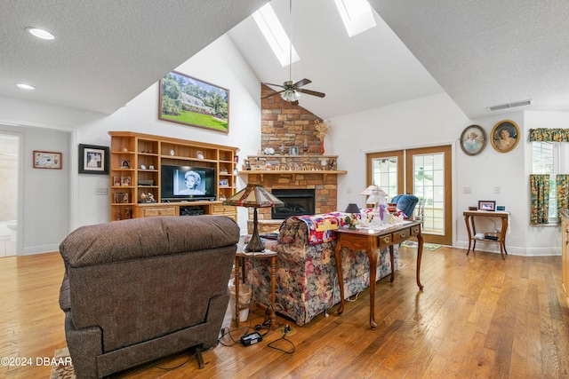 living room featuring light wood-type flooring, lofted ceiling with skylight, plenty of natural light, and ceiling fan