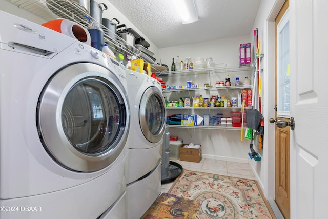 clothes washing area with washing machine and clothes dryer, light tile patterned floors, and a textured ceiling