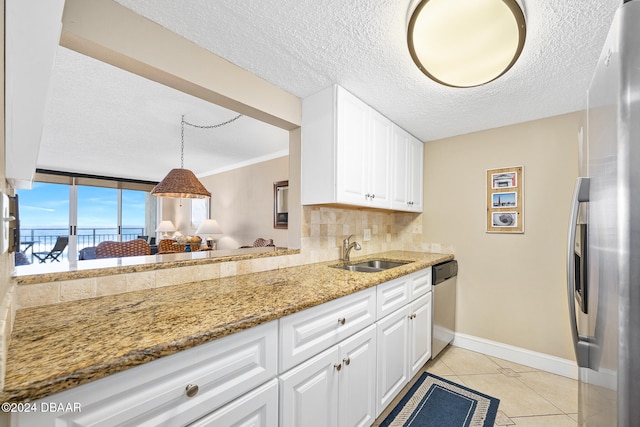 kitchen featuring white cabinets, a textured ceiling, light stone counters, and appliances with stainless steel finishes