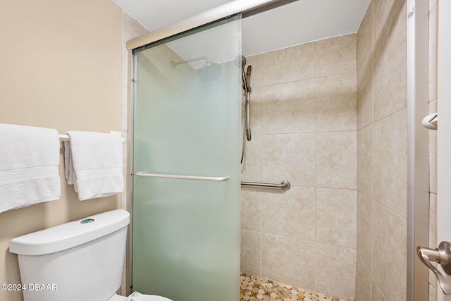 bathroom featuring toilet and a shower with door