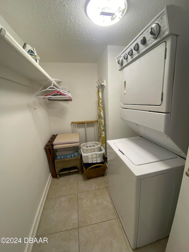 clothes washing area featuring stacked washer / dryer, a textured ceiling, and light tile patterned flooring