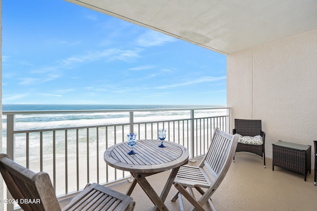 balcony with a water view and a view of the beach