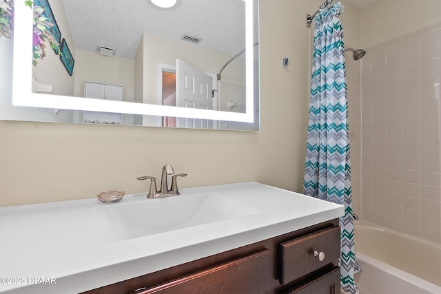 bathroom with vanity, shower / bathtub combination with curtain, and a textured ceiling