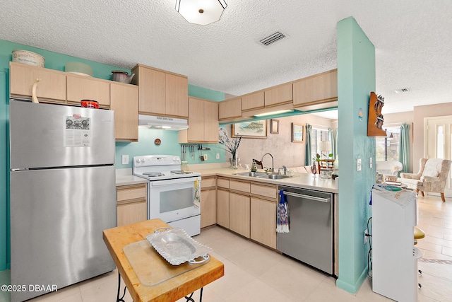 kitchen featuring appliances with stainless steel finishes, sink, light brown cabinets, and a textured ceiling