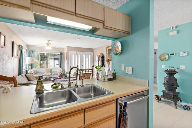 kitchen featuring light tile patterned flooring, sink, stainless steel dishwasher, ceiling fan, and a textured ceiling