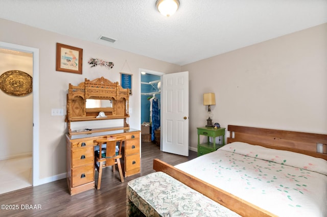 bedroom featuring dark hardwood / wood-style flooring, a spacious closet, a closet, and a textured ceiling