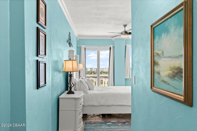 bedroom with ceiling fan, hardwood / wood-style flooring, ornamental molding, and a textured ceiling