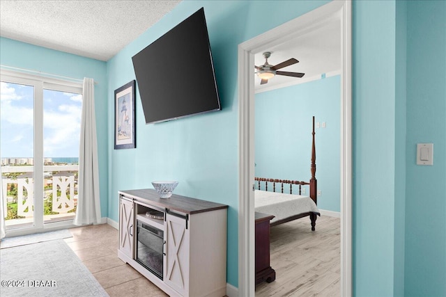 hallway with a textured ceiling, light hardwood / wood-style flooring, and a healthy amount of sunlight