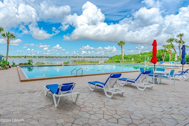 view of pool with a patio and a water view