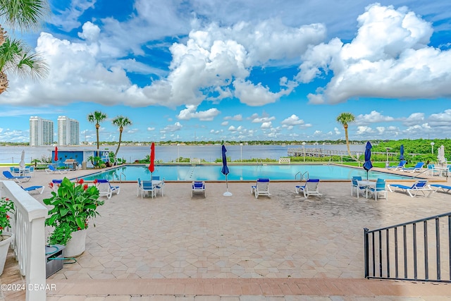 view of pool featuring a water view and a patio area