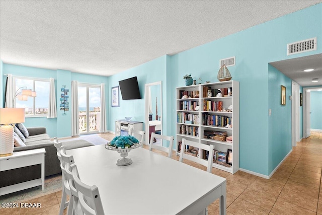 dining space with light tile patterned floors and a textured ceiling