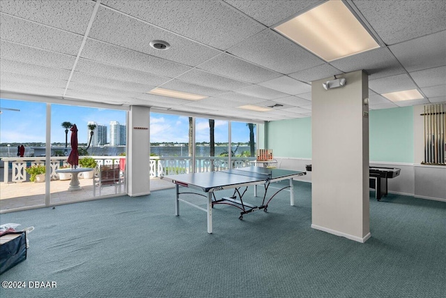 game room with a water view, a paneled ceiling, expansive windows, and carpet flooring