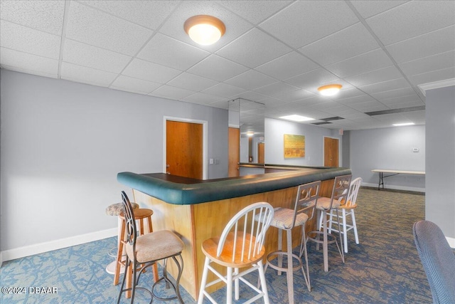 bar with a paneled ceiling and dark colored carpet