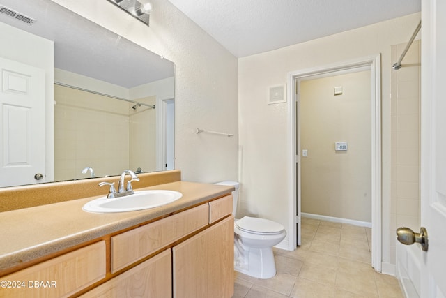 bathroom with a textured ceiling, vanity, a shower, tile patterned floors, and toilet