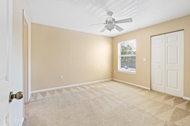 unfurnished bedroom with a textured ceiling, light colored carpet, ceiling fan, and a closet