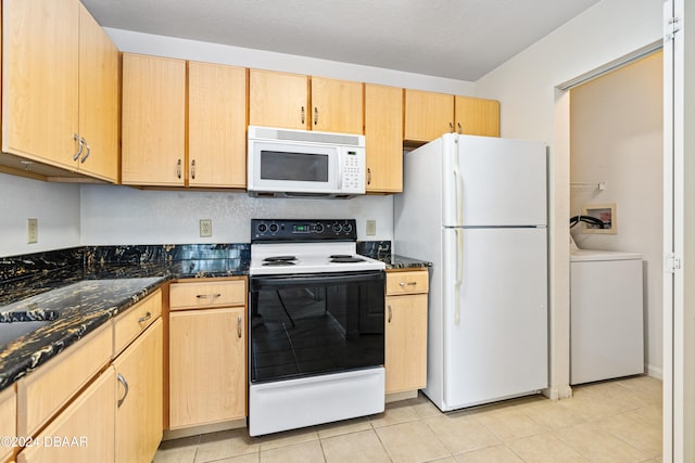 kitchen featuring dark stone countertops, light tile patterned floors, light brown cabinets, white appliances, and washer / dryer