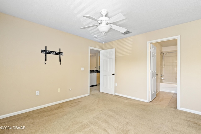 unfurnished bedroom with a textured ceiling, ensuite bath, light carpet, and ceiling fan