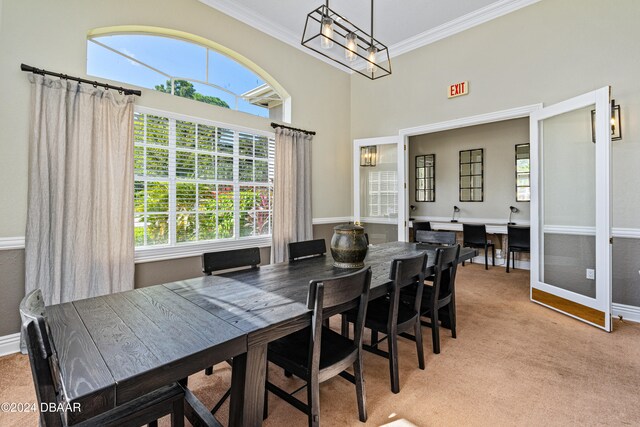 carpeted dining space featuring a towering ceiling and crown molding