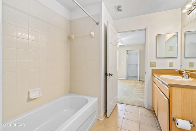 bathroom with vanity, tile patterned flooring, a textured ceiling, and tiled shower / bath