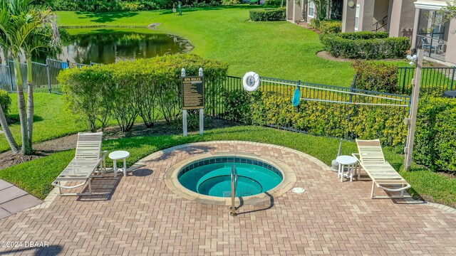 view of pool featuring a hot tub, a patio area, a water view, and a yard