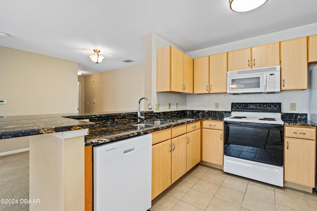 kitchen with kitchen peninsula, sink, light brown cabinetry, white appliances, and dark stone countertops