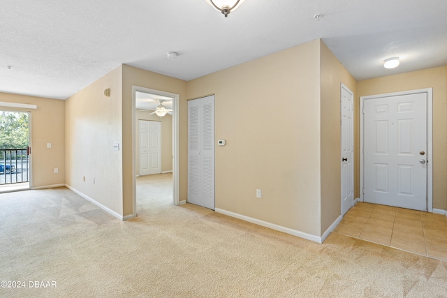 spare room with ceiling fan, a textured ceiling, and light carpet