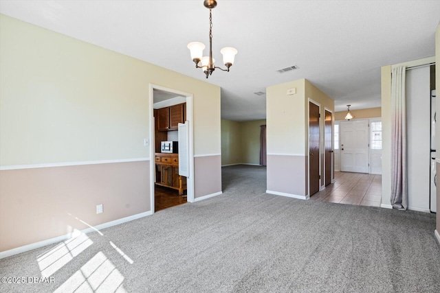 carpeted empty room featuring a notable chandelier