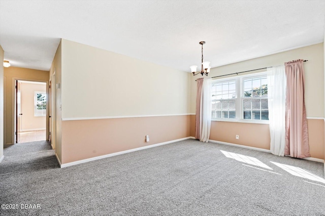 carpeted spare room featuring a notable chandelier