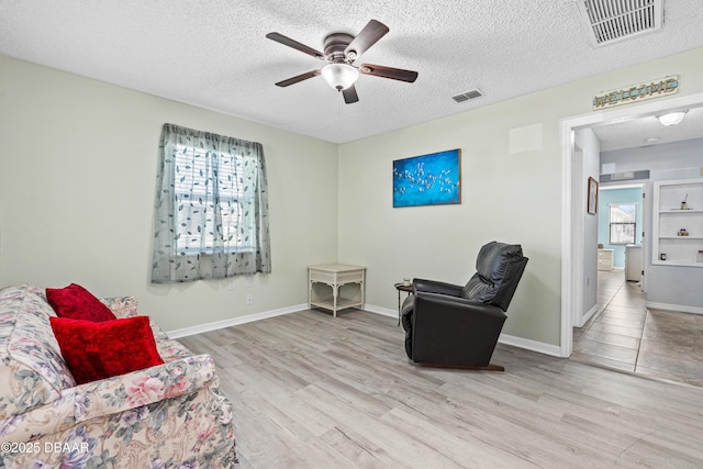 living area featuring plenty of natural light, a textured ceiling, and light hardwood / wood-style flooring