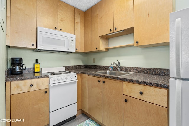 kitchen featuring white appliances, sink, and dark stone countertops