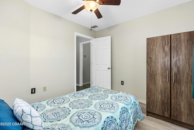 bedroom featuring light wood-type flooring, ceiling fan, and a closet