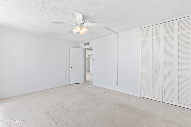 unfurnished bedroom featuring ceiling fan, a closet, light carpet, and a textured ceiling