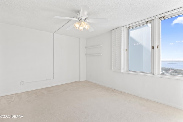 spare room with ceiling fan, light colored carpet, and a textured ceiling