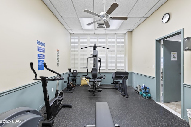 workout room featuring ceiling fan and a drop ceiling