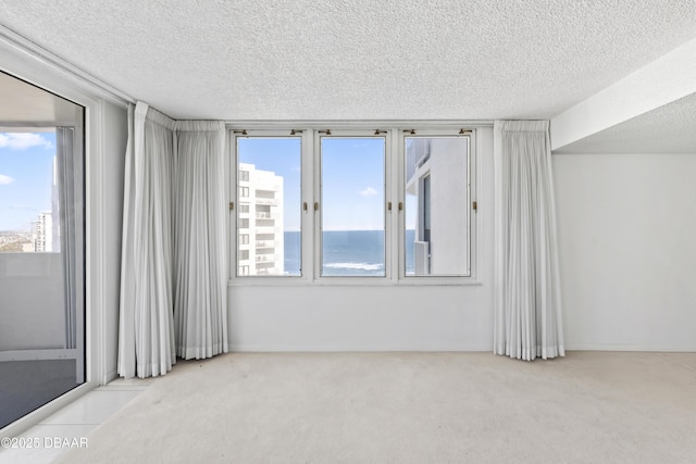 spare room with light carpet, a textured ceiling, and a water view