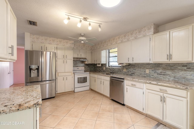 kitchen featuring sink, stainless steel appliances, white cabinets, and light stone countertops