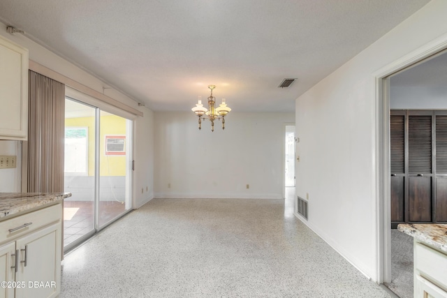 empty room featuring a notable chandelier and a textured ceiling