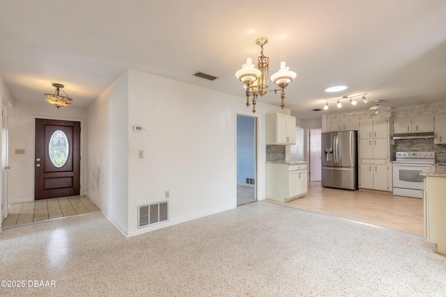 kitchen with white cabinetry, tasteful backsplash, hanging light fixtures, stainless steel fridge, and white range with electric cooktop