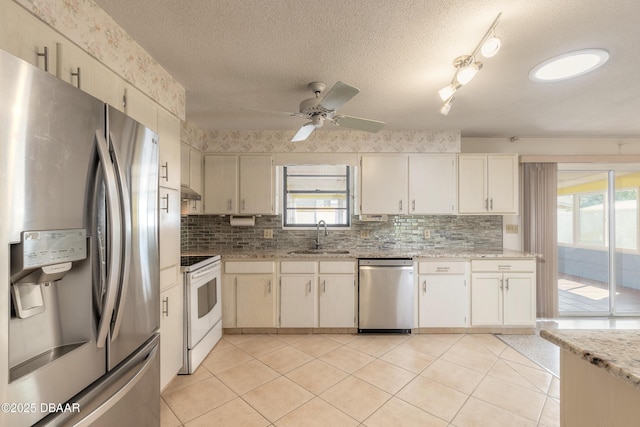 kitchen with light tile patterned flooring, sink, decorative backsplash, stainless steel appliances, and a textured ceiling