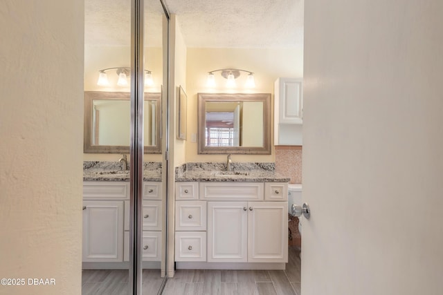 bathroom with vanity, toilet, and a textured ceiling