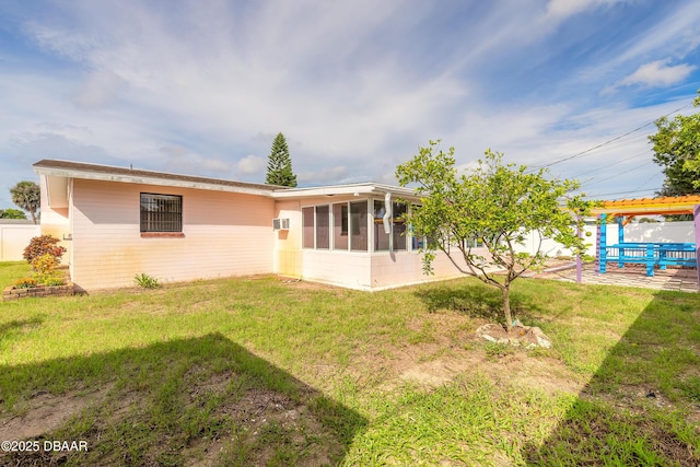 rear view of house featuring a yard, a patio area, a sunroom, and an AC wall unit