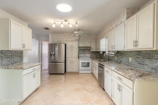 kitchen with sink, white cabinetry, light tile patterned floors, appliances with stainless steel finishes, and light stone countertops