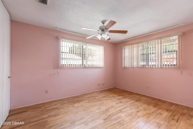 spare room with a textured ceiling, ceiling fan, and light wood-type flooring