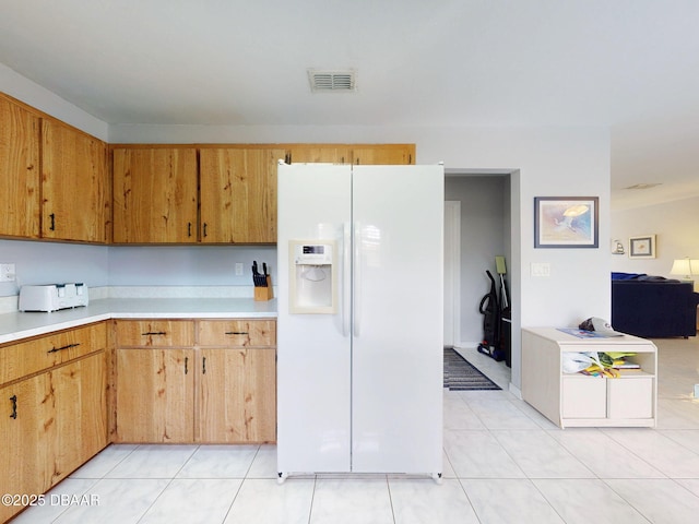 kitchen featuring light tile patterned floors, light countertops, white refrigerator with ice dispenser, and visible vents