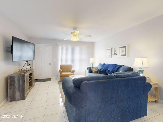 living area featuring light tile patterned floors, a ceiling fan, and baseboards